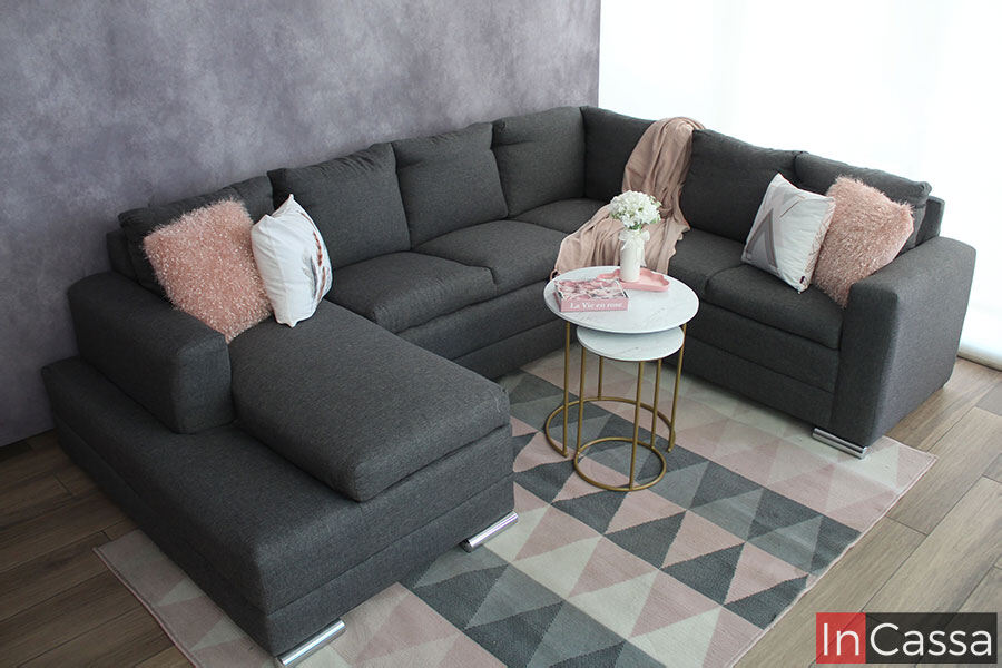 Sala en U tapizada en lino mouse, instalada en una estancia con piso de madera decorado con un amplio tapete y unas pequeñas mesas de centro.