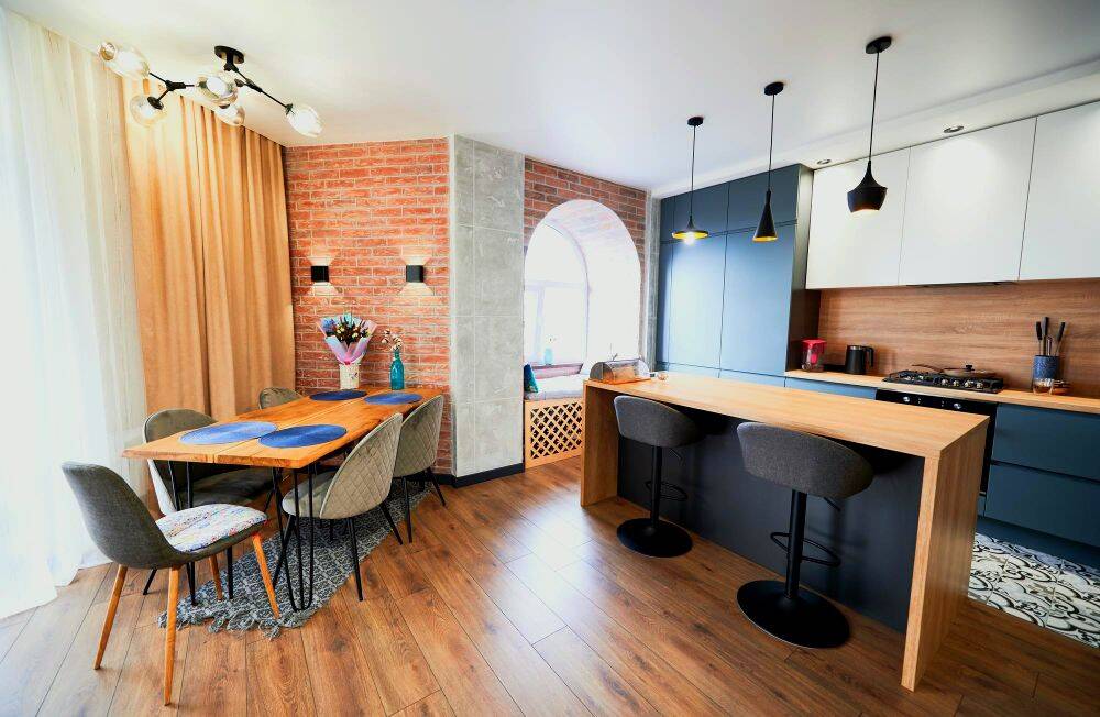 Una foto de un apartamento con un diseño interior minimalista con una estancia abierta, en la que podemos observar el comedor y la cocina en el mismo espacio.