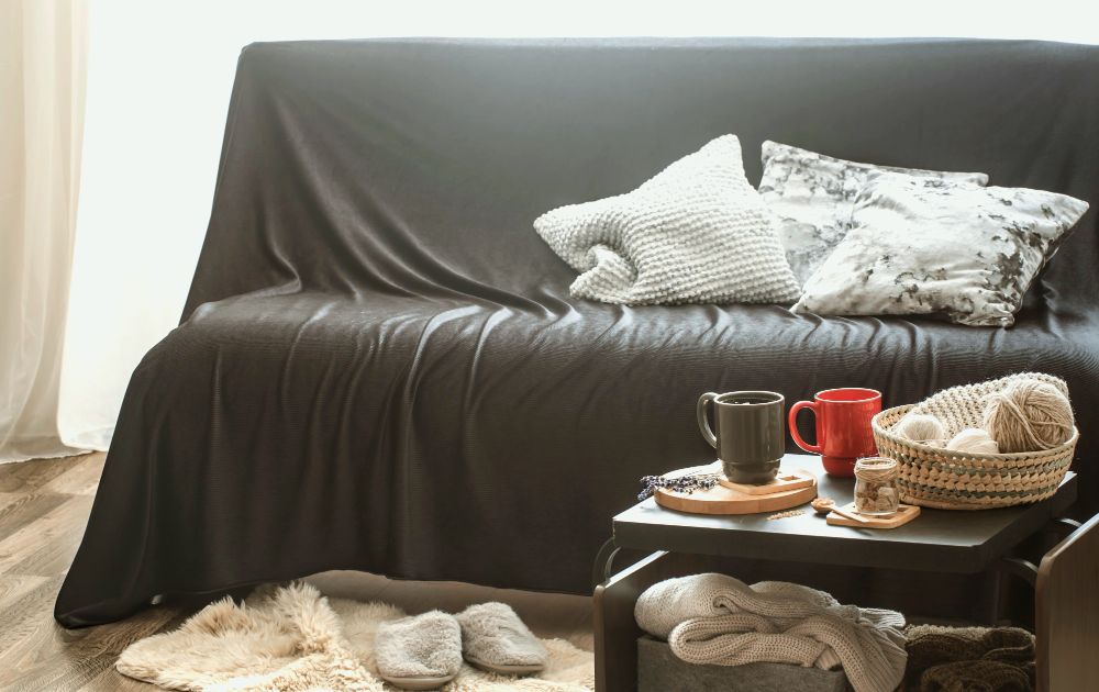 Un sofá cubierto por una ligera funda de color gris, dándole un decoración clásica del estilo escandinavo que además protege el mueble del polvo.