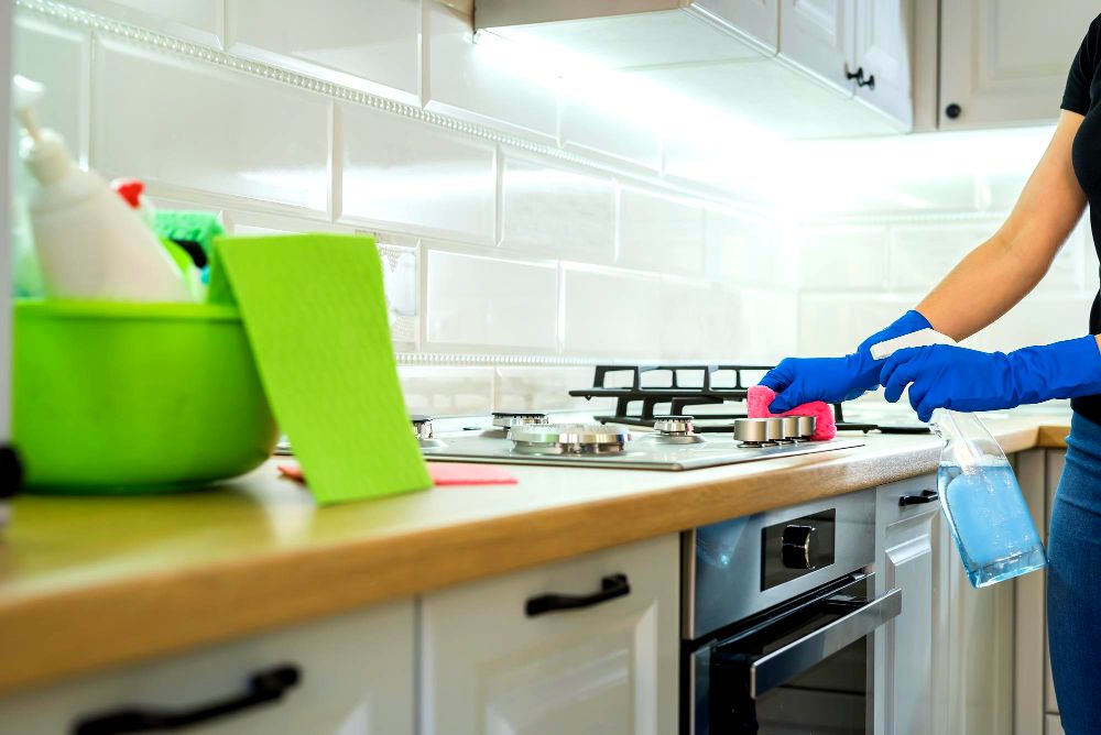 Foto de una persona limpiando su cocina, para lo cuál hace uso de varios utensilios.