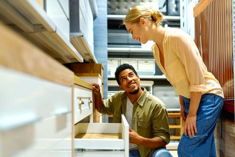 La imagen muestra a una pareja inspeccionando las cocinas de una tienda, a fin de encontrar la cocina perfecta para su hogar.