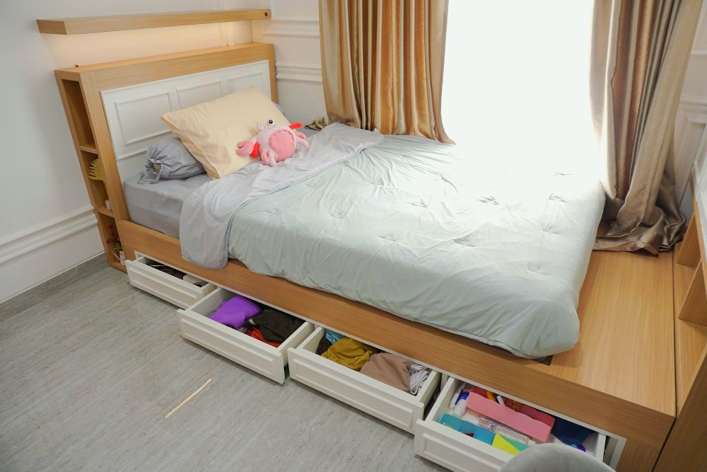 Un foto de una cama individual de madera, cuyo diseño incluye cuatro cajones en la base y algunos estantes en la cabecera.y pie de cama.