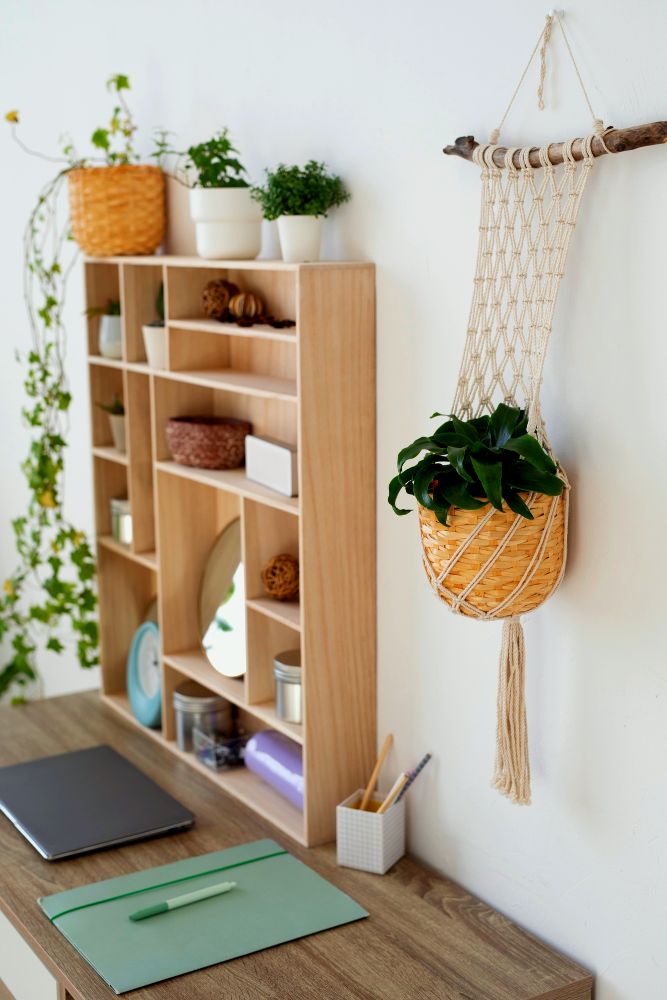 Vemos un pequeño escritorio minimalista con un estante de madera vertical con una gran variedad de compartimentos, el cual además está decorado con algunas plantas decorativas.