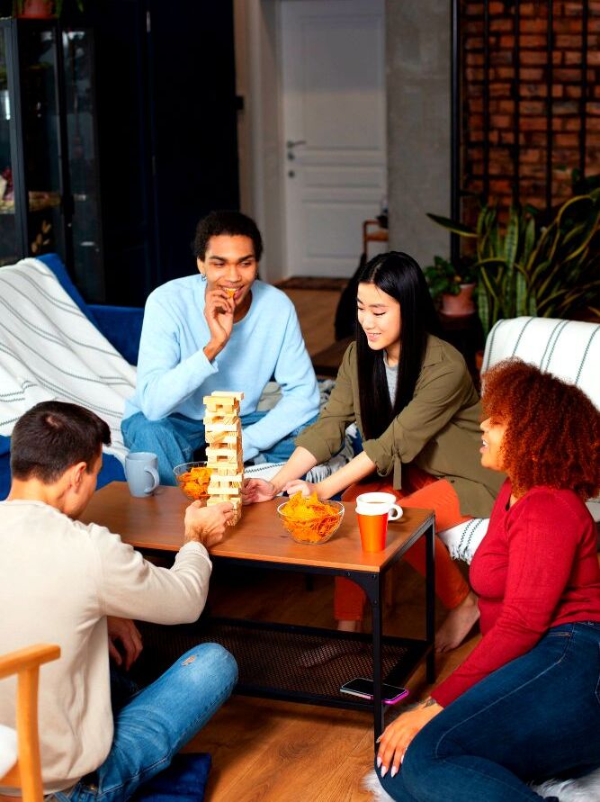 La foto muestra a un grupo de cuatro personas conviviendo alegremente con un juego de mesa en una estancia.