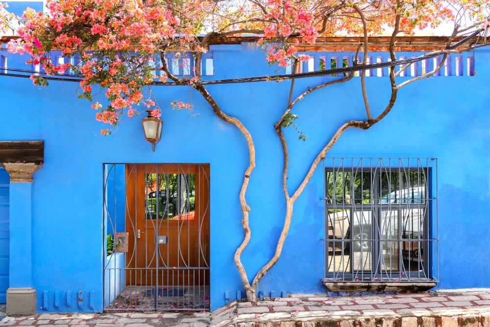 Una foto de la fachada de una casa la cuál es completamente de color azul, lo que le aporta serenidad al lugar.