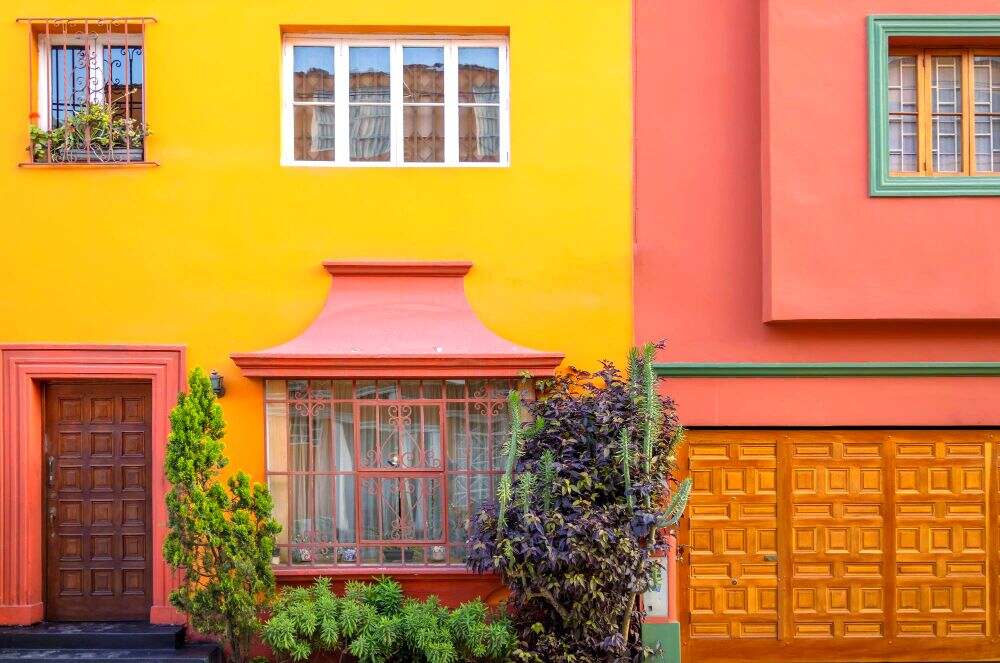 Una fotografía de una gran casa con una combinación de colores en el que el amarillo es el principal mientras que el secundario es mamey, todo complementado por detalles en color verde.