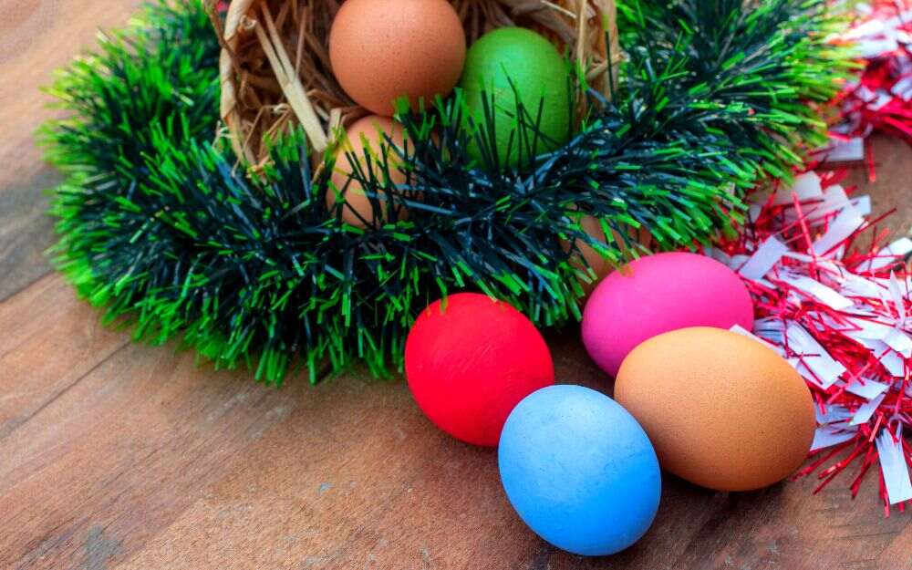 La imagen muestra una canasta con muchos huevos de Pascua acompañada de una guirnalda navideña.