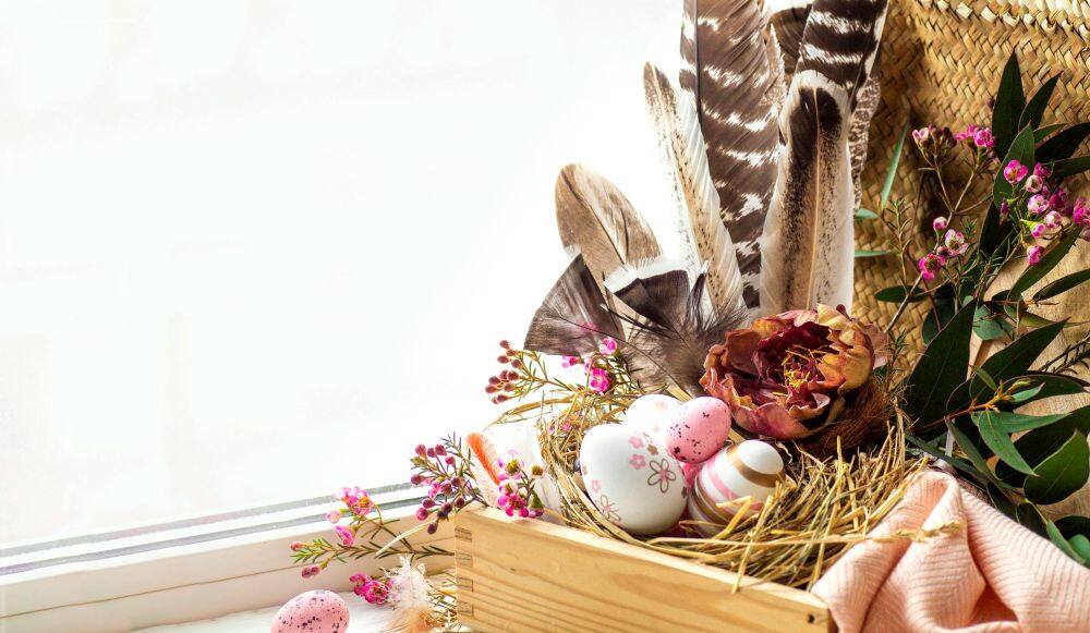 Foto de un tradicional nido de Pascua hecho en una caja de madera natural y decorado con una amplia variedad de flores y, por supuesto, varios huevos de pascua.