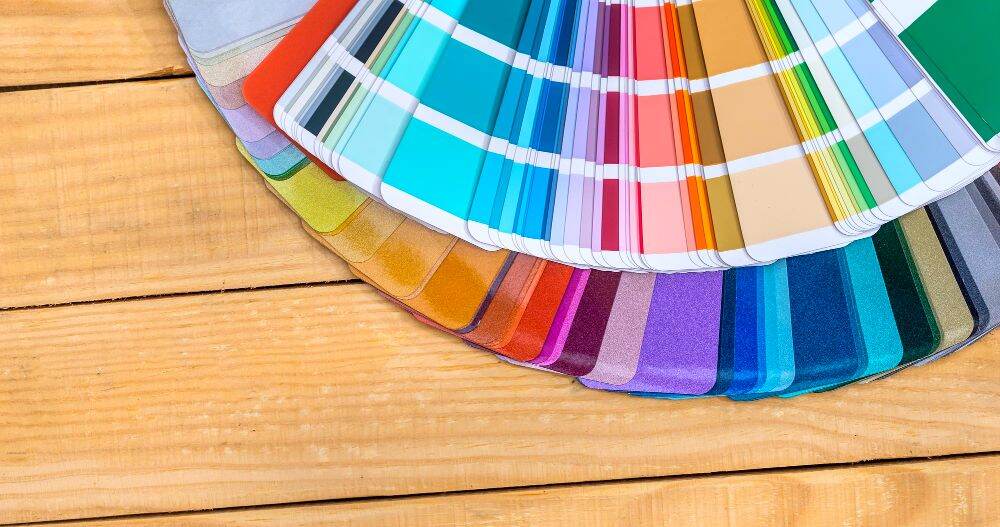 La imagen muestra una gran muestrario de colores en distintos tonos sobre una mesa de madera natural.