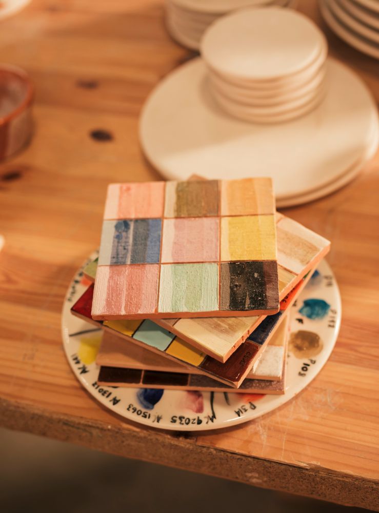La foto muestra un muestrario de paletas de colores con diferentes acabados y texturas sobre una mesa rustica de madera.