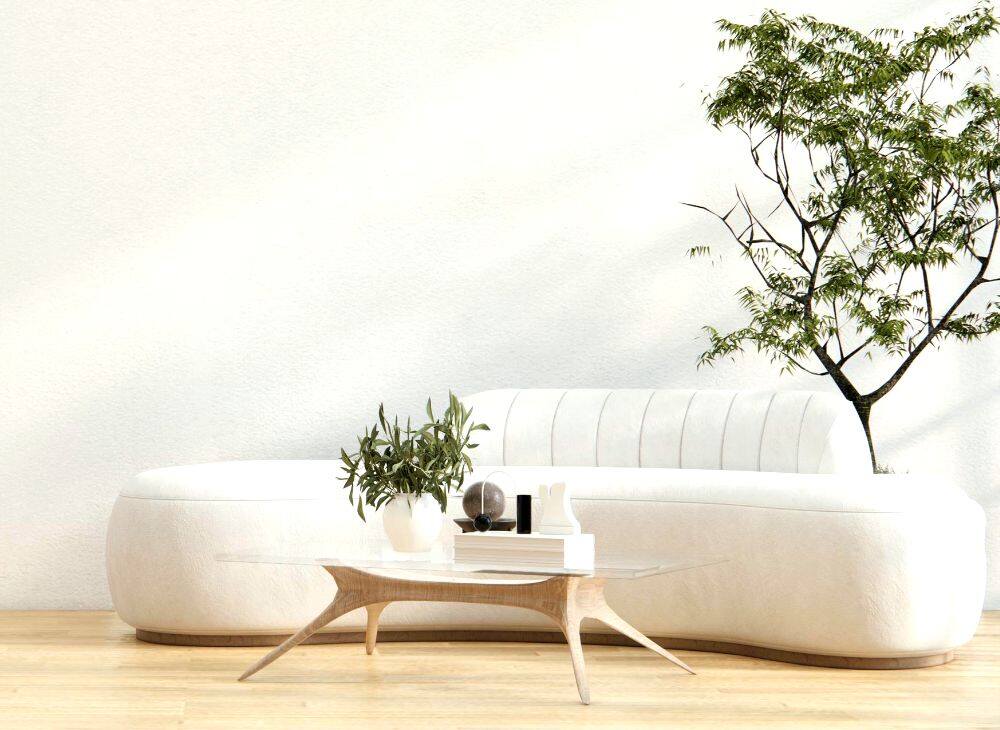 Un moderno sofá minimalista en tapiz blanco, acompañado por una mesa de centro con base de madera natural y cubierta de cristal, además de varias plantas decorativas.