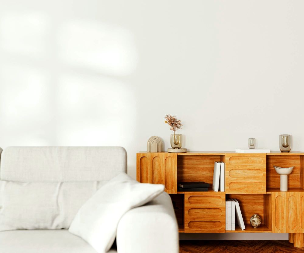 Una estancia con pared y sala blanca, en la que resalta un práctico mueble de madera natural, el cuál cuenta con varios estantes y cajones.