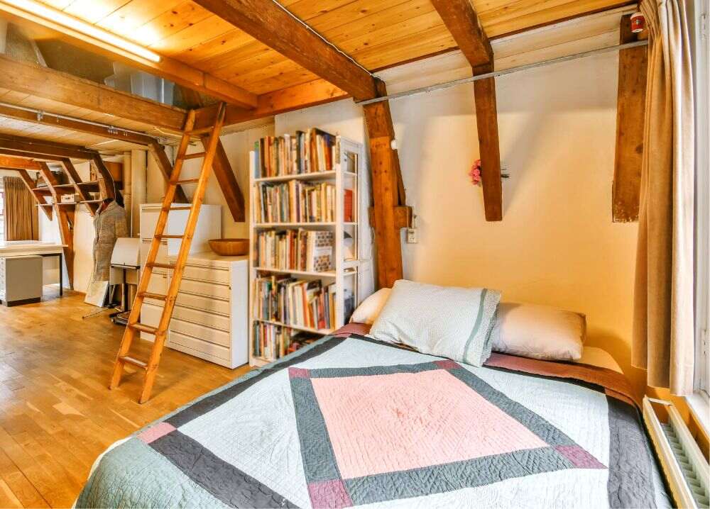 Foto de una recámara nórdica con muebles minimalistas blancos, entre los que se encuentran un librero con una gran colección de ejemplares impresos.
