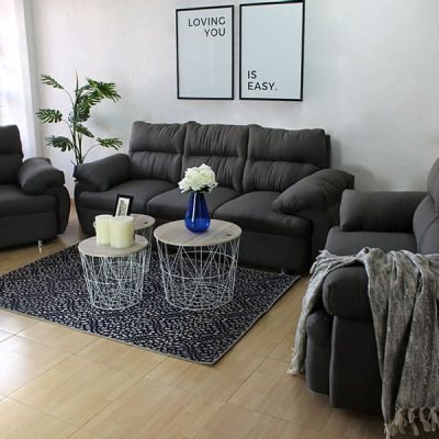 Sala Minimalista tapizada en lino mouse e instalada en una estancia con paredes blancas. La sala consta de un sofá de tres plazas, un love seat y un sillón; cada módulo cuenta con descansa brazos bastante amplios y patas metálicas con acabado cromado.