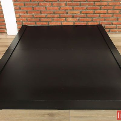 La imagen muestra una base de cama en acabado chocolate mate con líneas modernas y bordes elevados. Su estructura robusta proporciona estabilidad, mientras que su diseño minimalista la convierte en una opción sofisticada para cualquier dormitorio.