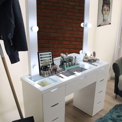 Tocador tipo vanity con 8 focos incluidos en su amplio espejo, el mueble cuenta con 8 cajones pequeños y uno más grande en el centro. La iluminación de los focos hace más notable su cubierta de cristal con la cuál se hacen perfectamente visibles los utensilios guardados en los 3 cajones superiores.