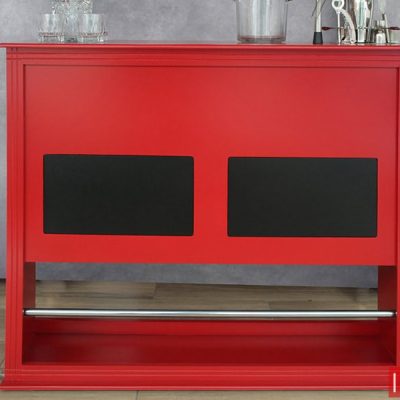 Barra cantina minimalista de color rojo con parches decorativos en color negro y una barra posa pies metálica, instalada junto a una pared gris.