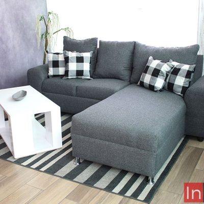 Se muestra la sala en escuadra desde una toma lateral, la cuál resalta el largo del chaise long de la sala y muestra más detalladamente la estructura completa del mueble, tapizado enteramente en tela lino color mouse.